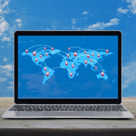 Map pin location button with connection line and world map on modern laptop computer on wooden table over blue sky with white clouds, Map pointer navigation online concept, Elements of this image furnished by NASA